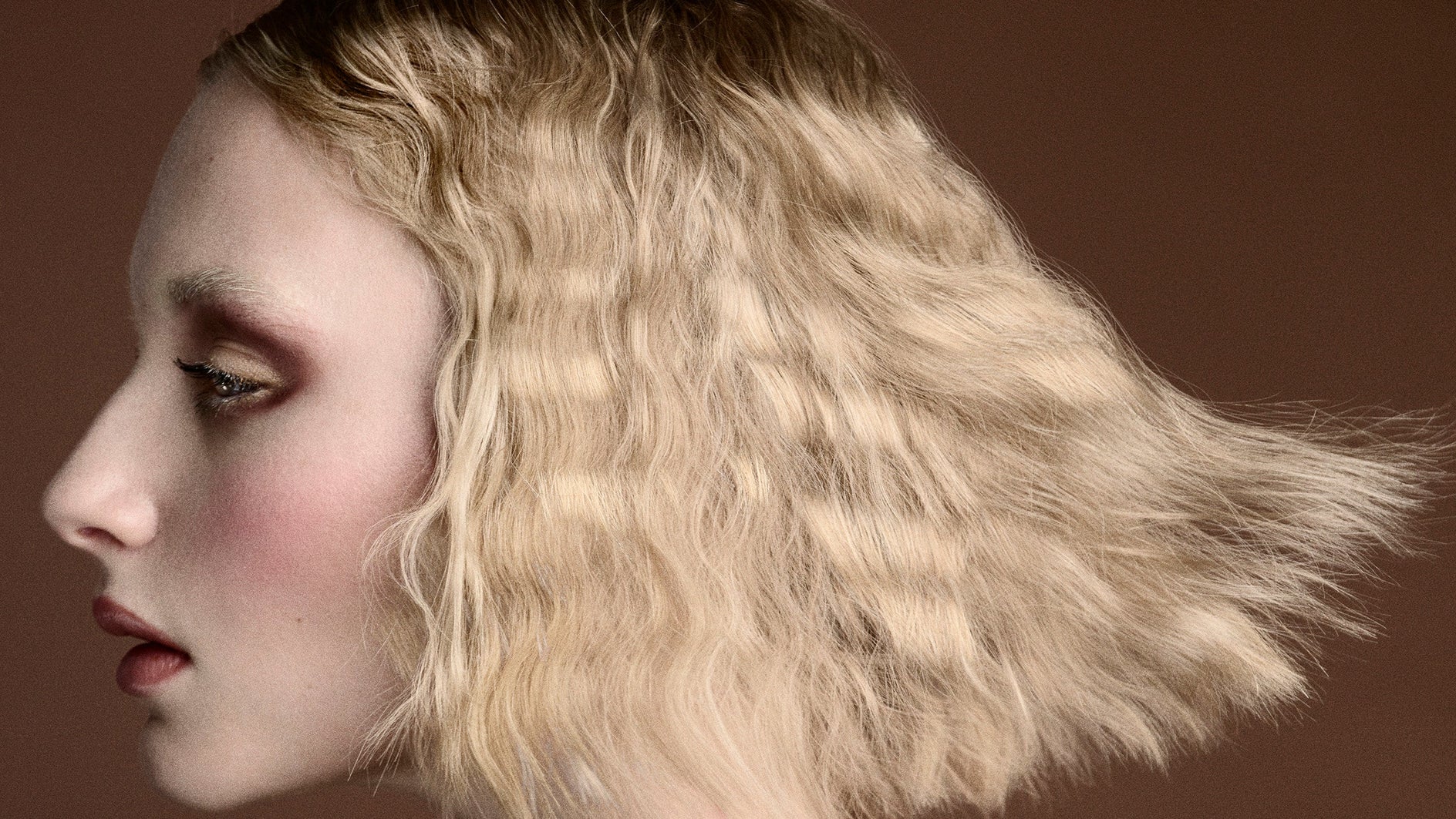 Woman with styled hair against a brown background