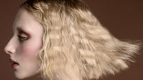 Woman with styled hair against a brown background