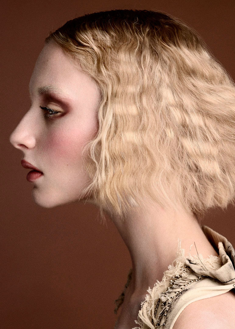 Woman with flowing blonde hair against a brown background