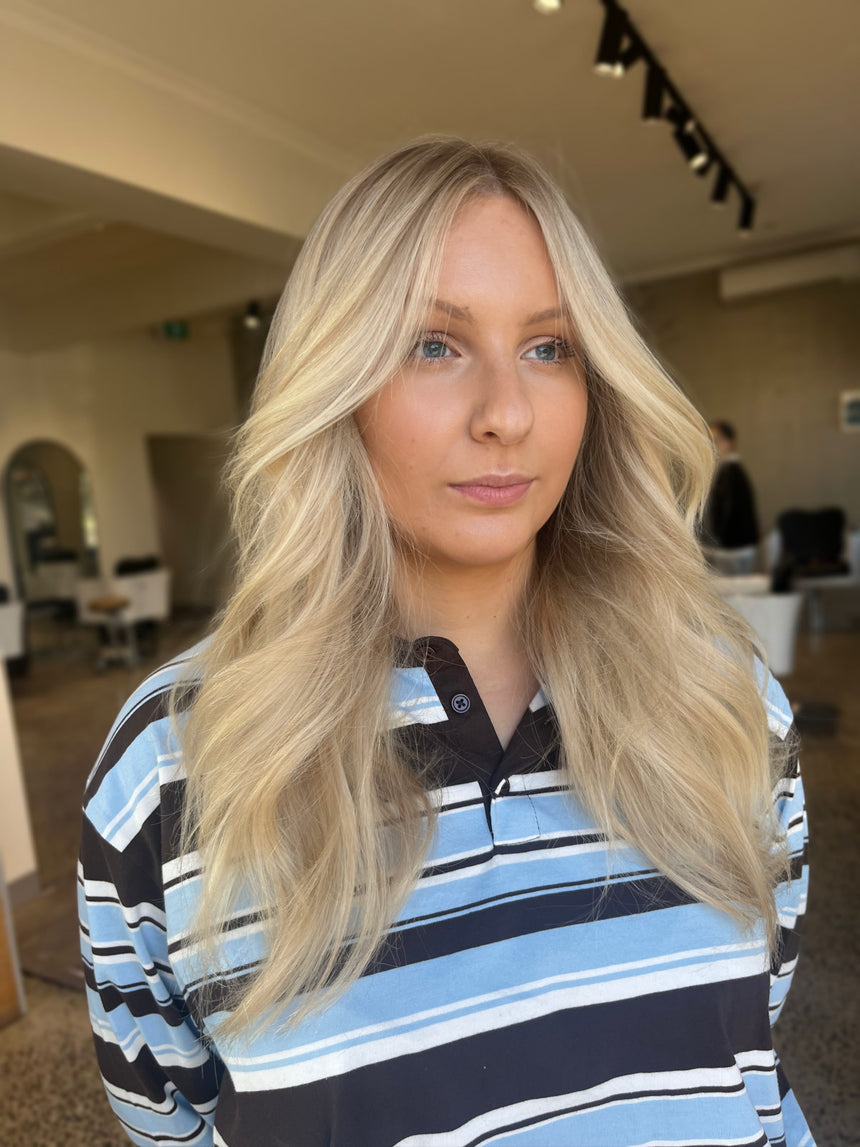 Woman with long blonde hair wearing a striped shirt indoors.