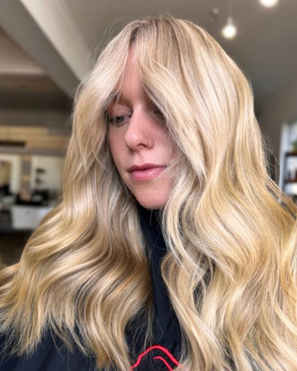 Person with long, wavy blonde hair in a casual setting.