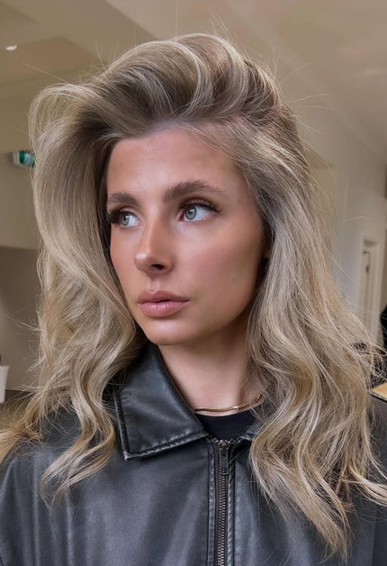 Woman with blonde hair wearing a black leather jacket indoors.