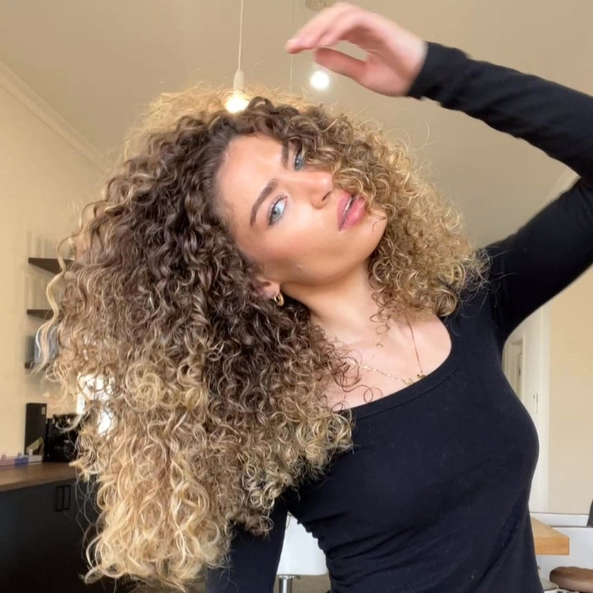 Woman with 3b curly blonde hair posing in a salon